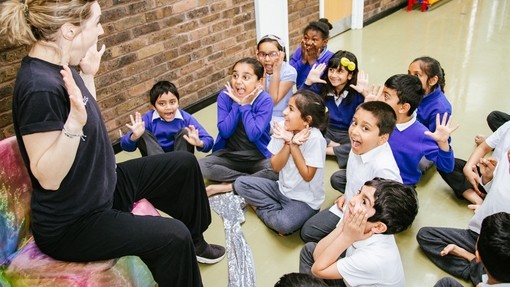 Animated storyteller facing a group of young pupils who have very excited facial expressions