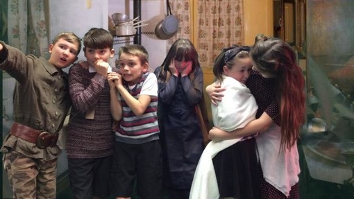 Young pupils performing in a play, gathered in a huddle looking scared