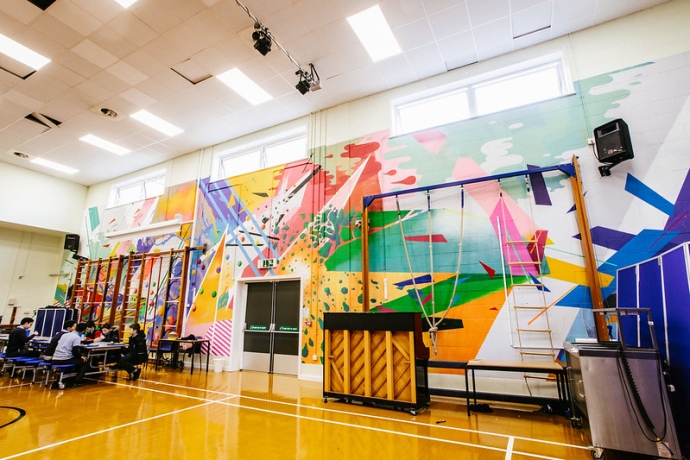 A school hall and gymnasium with brightly coloured abstract art across the whole of the back wall