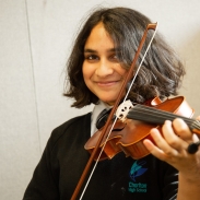 A school pupil playing the violin and looking at the camera. 