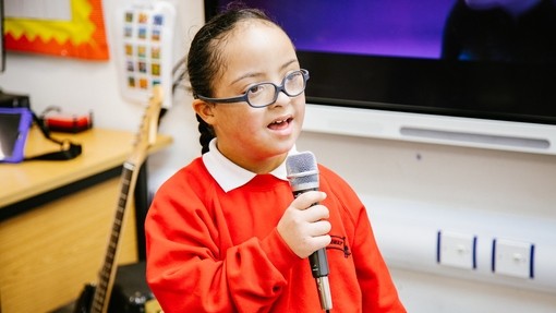 Young pupil singing into a microphone in a classroom environment