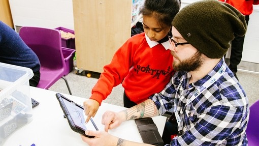 Male pupil and teacher looking at a tablet screen 