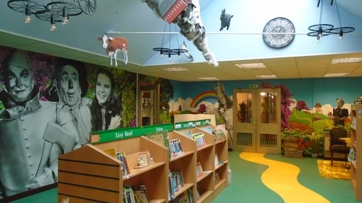 Race Leys Junior School library with Wizard of Oz themed wall mural and a yellow brick road on the floor leading to book shelves
