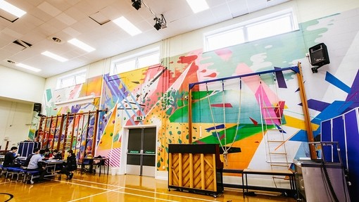 A school hall and gymnasium with brightly coloured abstract art across the whole of the back wall