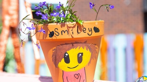 A terracotta plant pot with the words 'smiley' written on it and a drawing of a character smiling 