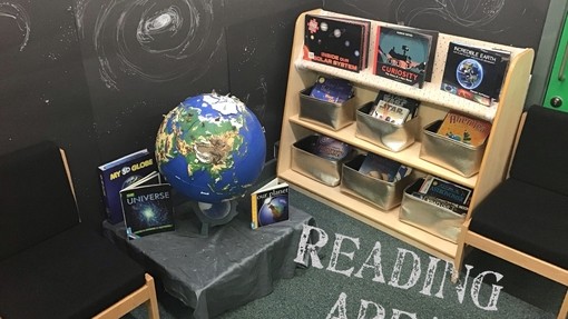 A corner of a room with low book shelf and a globe with the words 'reading area' overlaid onto the image 