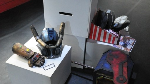 A variety of art, including handmade helmets, stood on stands at an exhibition. 