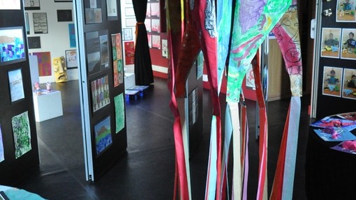 Colourful clothes hung up, exhibited on a stand at an exhibition. 