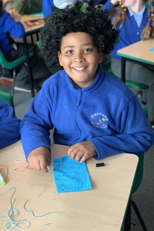 Pupil learning to sew and smiling proudly 