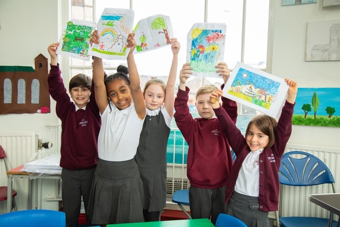 Children looking happy holding up drawings above their heads in a classroom setting 