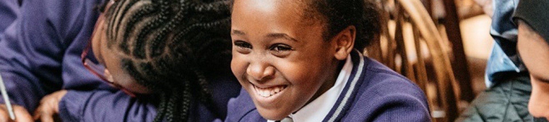 Young female pupil smiling and writing at a First Story workshop in Oxford