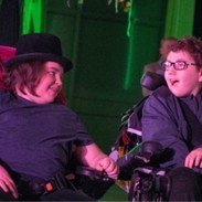 Two young boys in wheelchairs, performing on stage