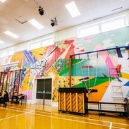 A school hall and gymnasium with brightly coloured abstract art across the whole of the back wall