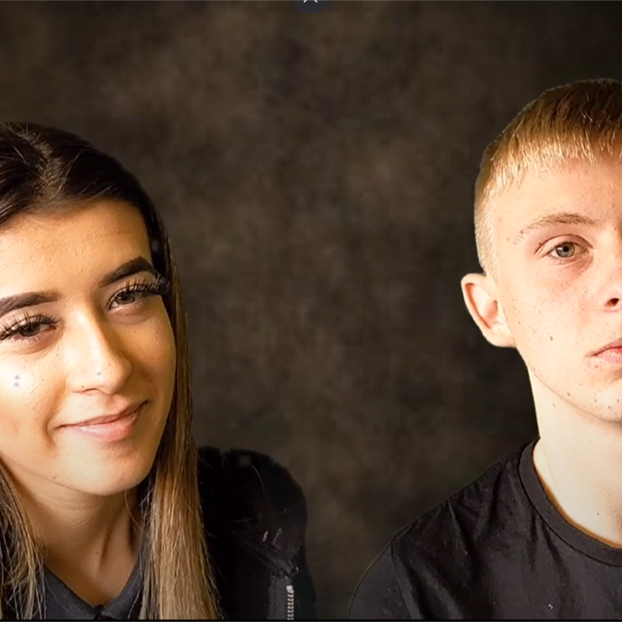 Two students look straight into the camera, there is a dark background behind them.